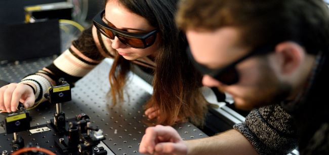 Two students in safety glasses working on a quantum technology project.